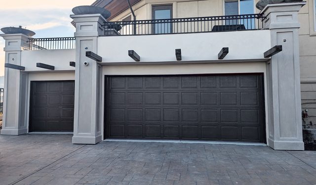 A gate house with garage doors in coated stone.