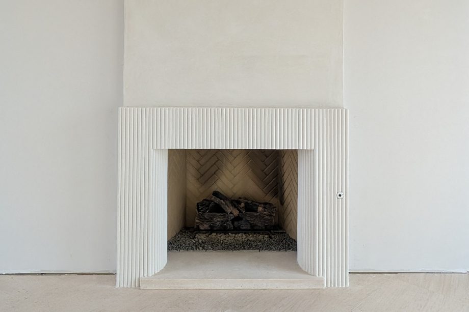 A white fluted fireplace surround.