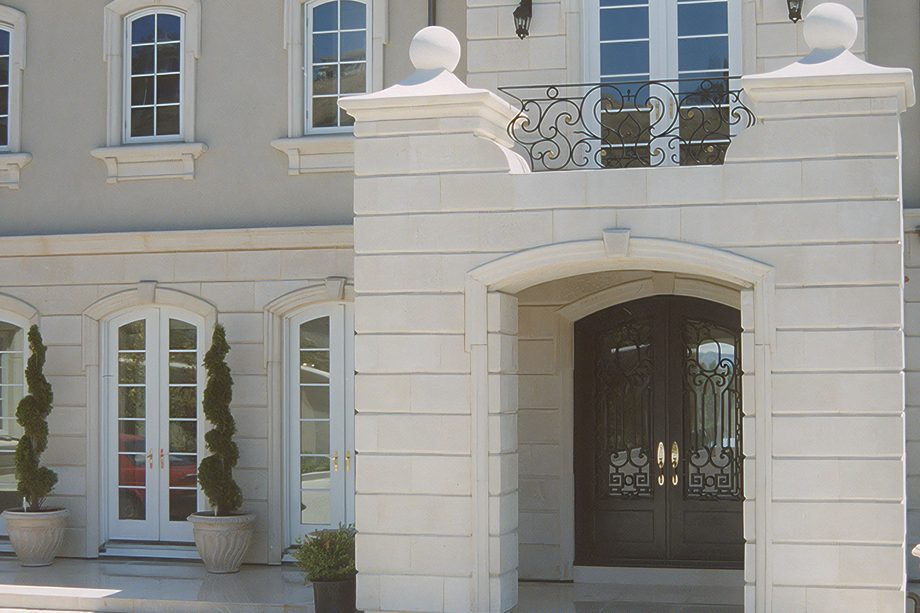 A white block entry gate with an iron balcony.